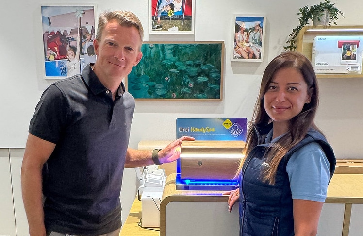 Drei CCO-Günter Lischka und eine Shop-Mitarbeiterin mit der UV-Reinigungsbox im "HandySpa" des Drei-Shops.