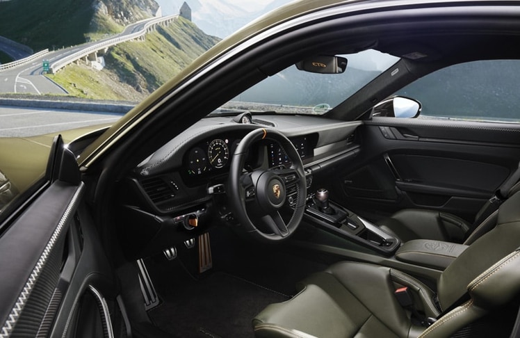 Dekorative orangefarbene Nähte und der gestickte Schriftzug "GT3" auf den Kopfstützen übertragen die "Alpenglühen"-Farbtöne in den Innenraum, ebenso wie Akzente am Gaspedal, an der 12-Uhr-Markierung am Lenkrad, am Schalthebel und an Details der GT Sport Chrono Uhr. © Dr. Ing. h.c. F. Porsche AG/Porsche Holding